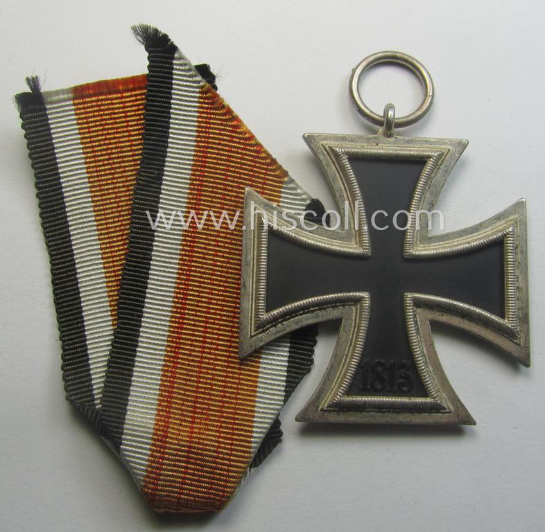Iron Cross 2nd class (or: 'EK II. Klasse') being a non-maker-marked example that comes together with its original (shortened and orange-red-coloured) ribbon (ie. 'Bandabschnitt') as was produced by the desirable 'C.E. Juncker'-company