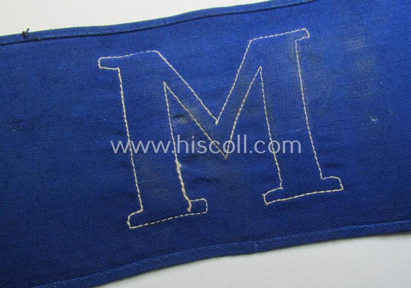 Neat, linnen-based- and/or blue-coloured armband (ie. 'Armbinde') depicting a felt-woolen-based, capital 'M'-character as was presumably intended for staff-members (ie. 'Melder') of the German RLB (ie. 'Reichsluftschutz-Bund')
