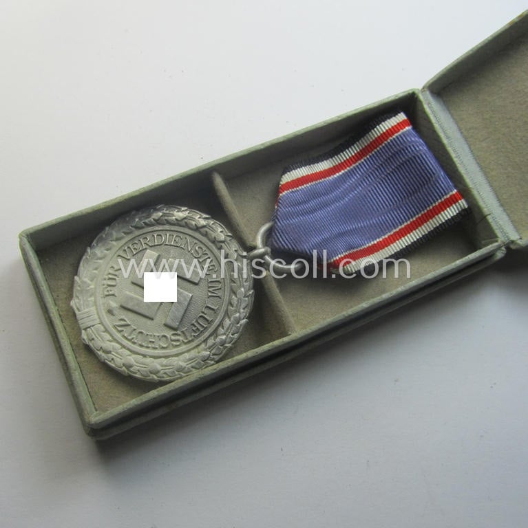 Light-weight (ie. typical aluminium-based) medal as was intended for air-raid wardens 2nd. class (or: 'Luftschutz-Ehrenzeichen 2. Stufe') that comes stored in its period, dove-grey-coloured etui