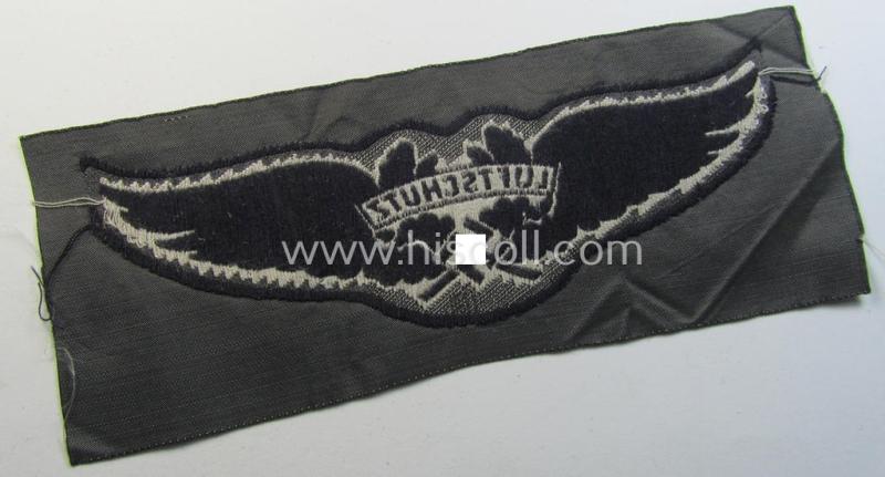 Attractive - and scarcely encountered! - EM- (ie. NCO-) pattern, so-called: 'Luftschutz' (ie. RLB-) breast-badge (ie. 'Brustabzeichen') as executed in so-called: 'BeVo'-weave-pattern and that comes in a 'virtually mint- ie. unissued' conditio...