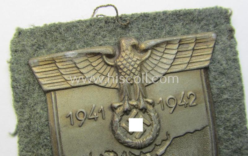 Attractive, WH (Heeres o. Waffen-SS) 'Krim'-campaign-shield that comes mounted onto its original, field-grey-coloured 'backing' and that comes in a surely issued-, minimally worn and/or (I deem) carefully tunic-removed-, condition