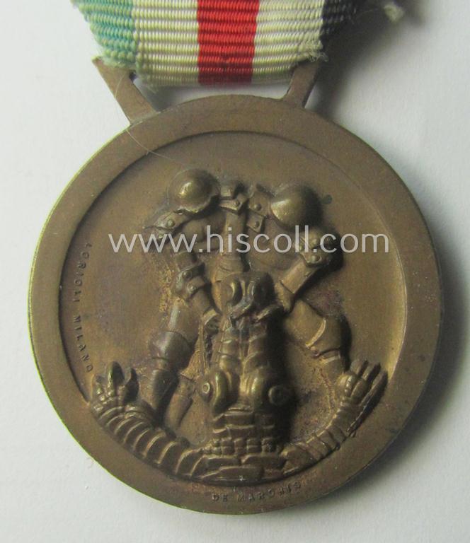 Golden-bronze-coloured- (and I deem 'Buntmetall'-based-) example of a: 'Deutsch-Italienische Feldzugsmedaille' (or: German-Italian campaign-medal) that comes mounted onto its (regular-sized) piece of original (and hardly faded!) ribbon