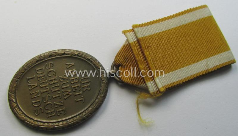 Medal-set: 'Deutsches Schutzwall Ehrenzeichen' (aka: 'Westwall'-medal) being a non-maker-marked- and/or: 'Buntmetall'-based specimen that comes mounted onto its period- (and neatly folded ie. pre-confectioned) ribbon (ie. 'Bandabschnitt')
