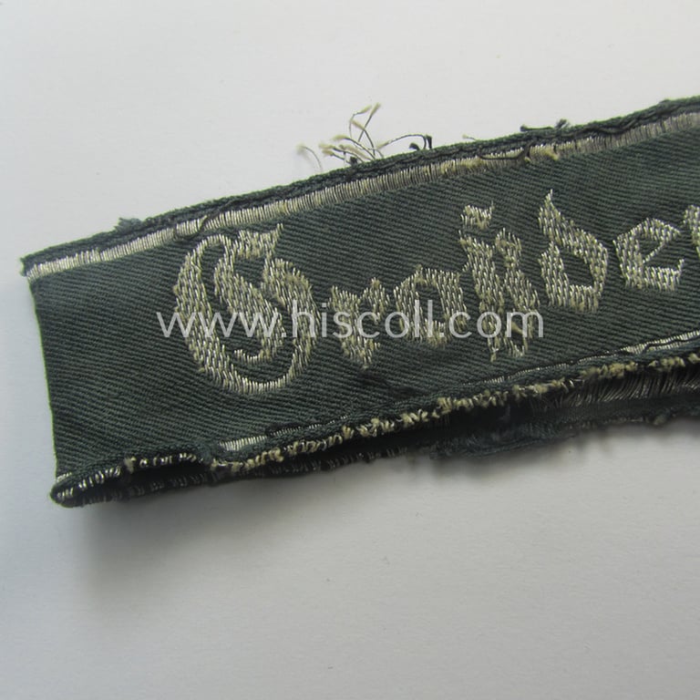Truly worn- (ie. relic) example of the - rarely encountered! - WH (Heeres) EM- (ie. NCO-) type 'Grossdeutschland'-cuff-title (ie. Ärmelstreifen) being a shortened example of the 1st pattern (as executed in so-called: 'BeVo-flat-wire-woven'-pattern)