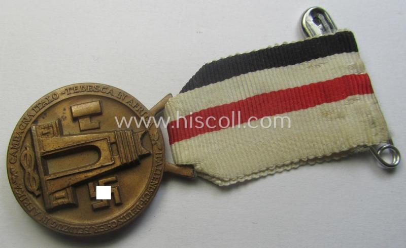 Golden-bronze-coloured- (and I deem 'Buntmetall'-based-) example of a: 'Deutsch-Italienische Feldzugsmedaille' (or: German-Italian campaign-medal) that comes mounted onto its (regular-sized) piece of original (and somewhat faded!) ribbon