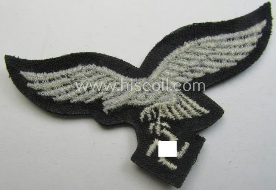 WH (Luftwaffe) cap-eagle (being a 'standard-issue'-pattern example that is executed onto a black-coloured background and that was as such intended for usage on the black-coloured work- ie. 'HG'-related side-caps ie. 'Schiffchen')