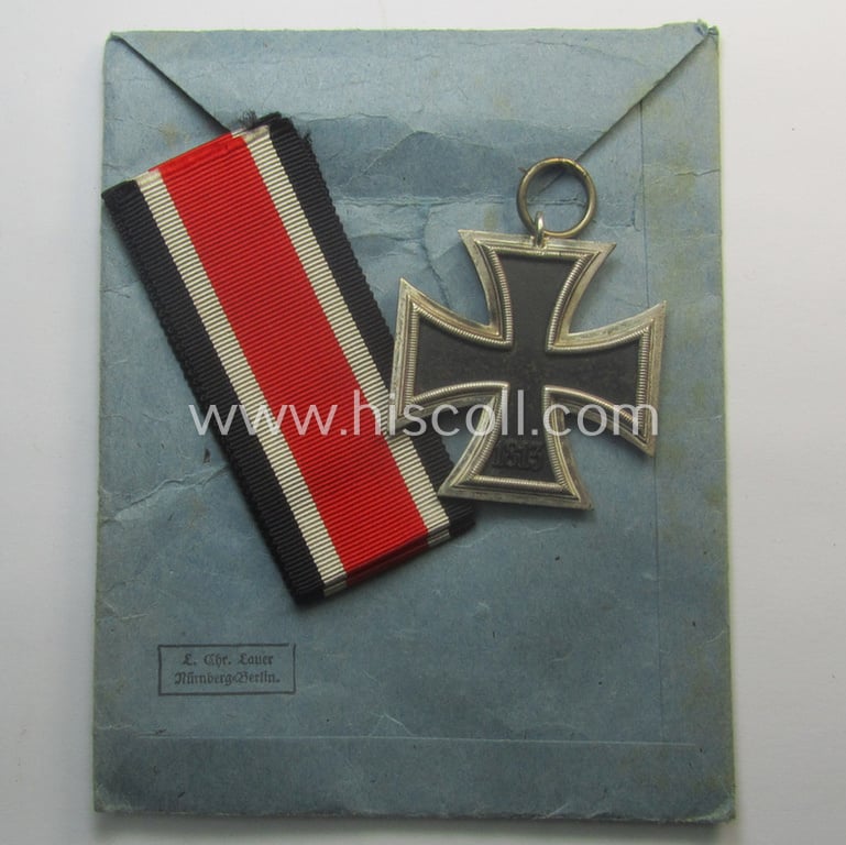 Matching 'EK II. Klasse'-set comprising of a non-maker-marked specimen that comes with its ribbon (ie. 'Bandabschnitt') and 'Zellstoff'-based pouch as was produced by the company: 'L.Chr. Lauer' (ie. 'Hersteller 14')