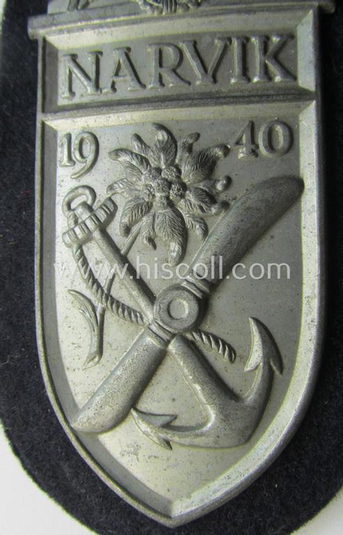 Superb - and scarcely encountered! - WH (KM) 'Narvik'-campaign-shield being a detailed example as executed in ('migriertes') golden-toned zinc- (ie. 'Feinzink') and that comes in an issued- (albeit I deem never worn- nor tunic-attached-), condi...