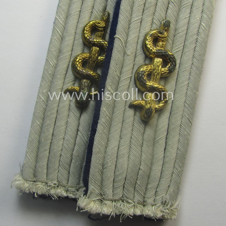 Pair of neatly 'cyphered', WH (Heeres) officers'-pattern shoulderboards as piped in the darker-blue-toned branchcolour as was specifically intended for a: 'Leutnant u. Arzt einer Sanitäts-Abtlgs.'