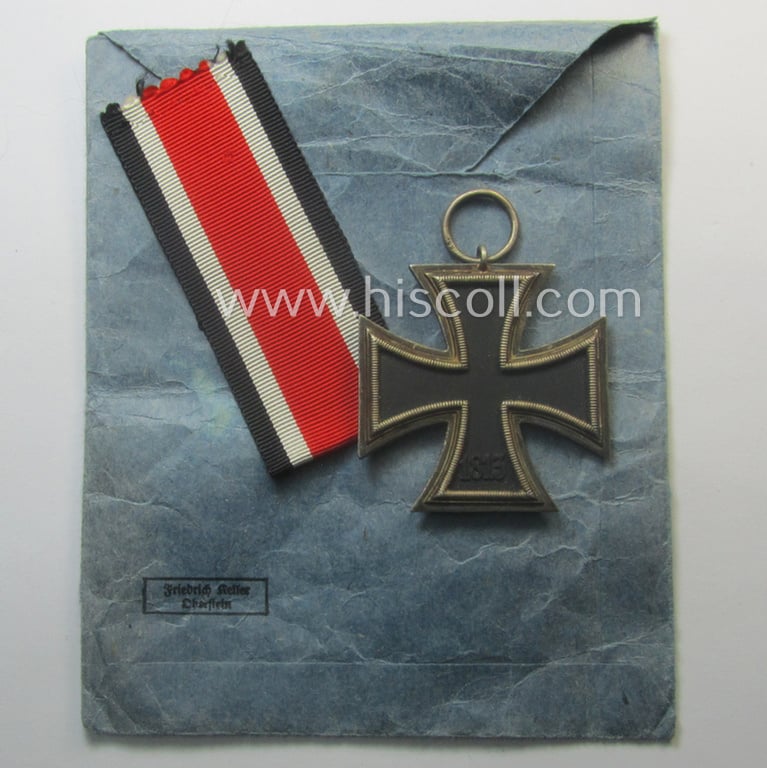 Fully matching 'EK II. Klasse'-set comprising of a neatly-maker- (ie. '66'-) marked specimen that comes with its ribbon (ie. 'Bandabschnitt') and 'Zellstoff'-based pouch as was produced by the company: 'Friedrich Keller' (ie. 'Hersteller 66')