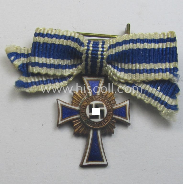 Attractive, 2-cms.-sized miniature of a maker- (ie. 'L/60'- ie. by 'GB'-) marked: 'Ehrenkreuz der Deutschen Mutter in Bronze' that came stored in its non-maker-marked, two-pieced bordeaux-coloured 'LDO'-type box (ie. etui)