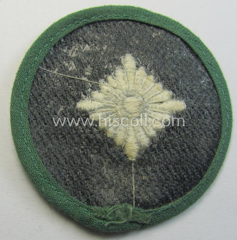 Attractive, WH (Heeres) rank-insignia (ie. arm-roundel) as was specifically intended for usage by an: 'Oberschütze' (being an interesting example as executed in silverish-grey-coloured linnen onto a 'HBT'-type, greenish-coloured background)
