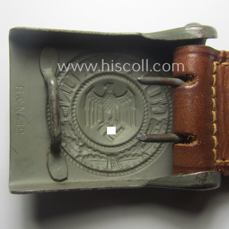 WH (Heeres) 'standard-pattern', field-grey-toned- and steel-based belt-buckle being a maker- (ie. 'Berg u. Nolte - Lüdenscheid'-) marked- and/or: '1942'-dated example that comes mounted onto its leather-based tab