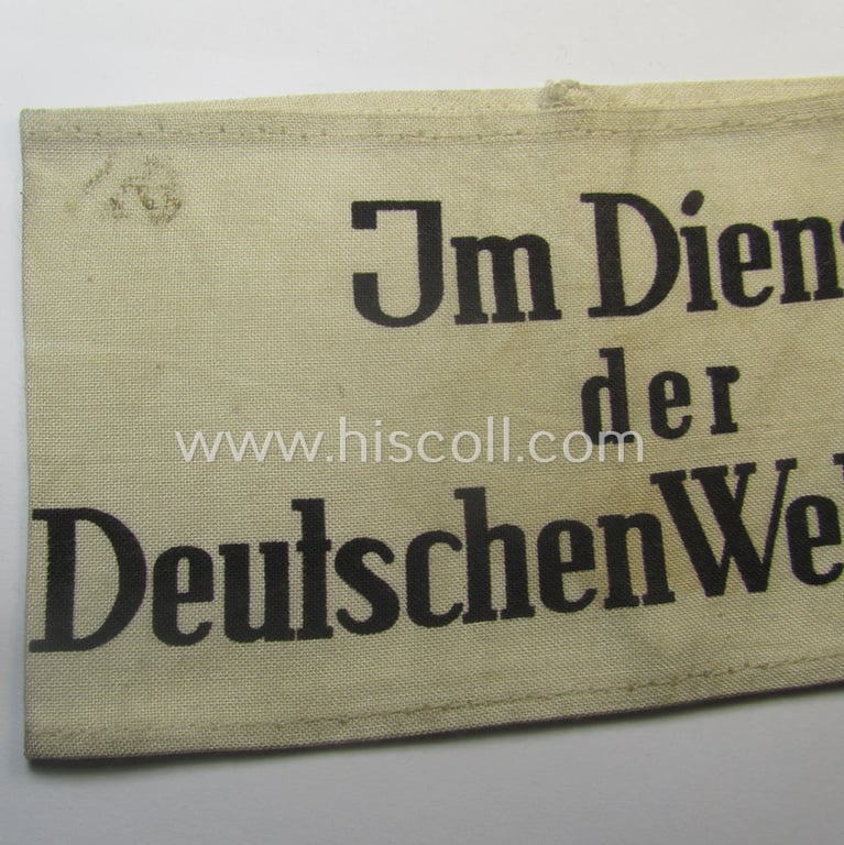 Linnen-based- and/or neatly printed, white-coloured armband (ie. 'Armbinde') entitled: 'Im Dienst der Deutsche Wehrmacht' as was intended for (civilian) staff-members serving within the German armed forces ie. 'Deutsche Wehrmacht'