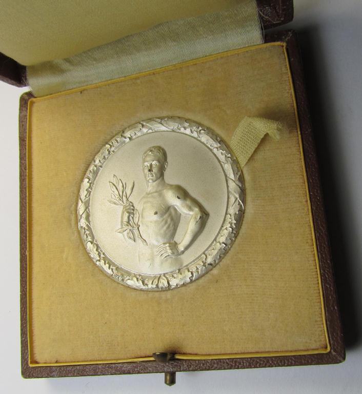 Interesting, D.D.A.C.-related, commemorative plaque (ie. 'Erinnerungs- o. nichttragbare Auszeichnungsplakette') showing an illustration of a sportsman and on its back the text: 'II. Preis Dreikampf Männer 1938' and that comes stored in its period...