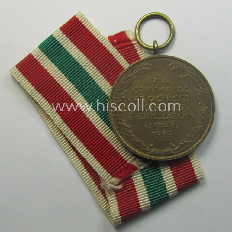 WH Memelland 'Anschluss'- (ie. occupation-) medal: '22 März 1939' (being a minimally used example of the so-called: 'slanted G'-type) that comes together with its original non-confectioned ribbon (ie. 'Bandabschnitt')