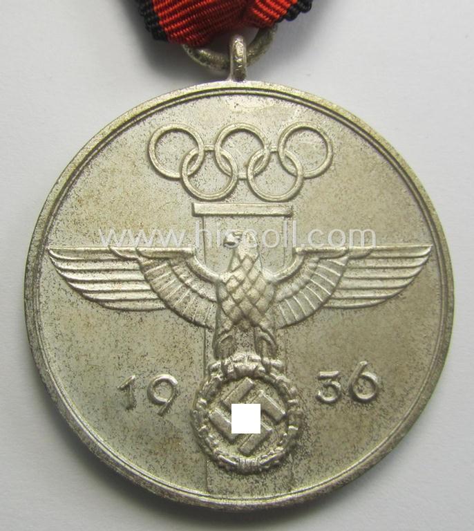 'Deutsche Olympia-Erinnerungsmedaille 1936' being a non-maker-marked example that comes mounted onto its original ribbon (ie. 'Bandabschnitt') and that comes stored in its typical, beige-white-coloured etui