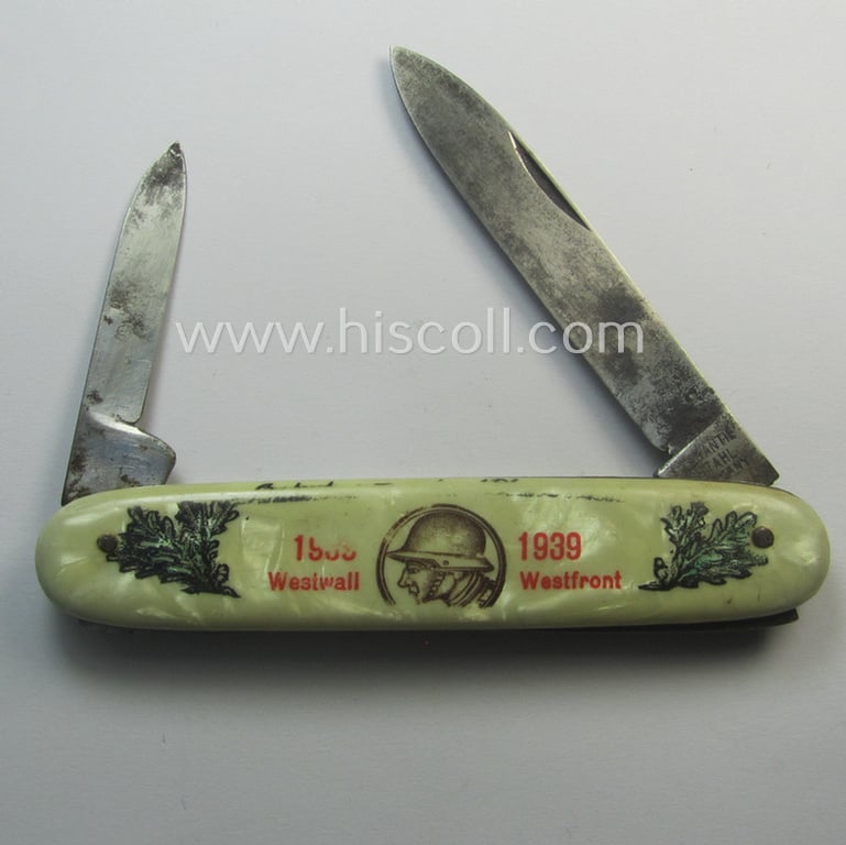 Interesting, (pre-) WWII-period 'souvenir-item' (ie. tiny pocket-knife) showing on its front an illustration of a soldier wearing a steel-helmet flanked by oakleaves coupled with the text: '1938 - 1939 - Westwall - Westfront'