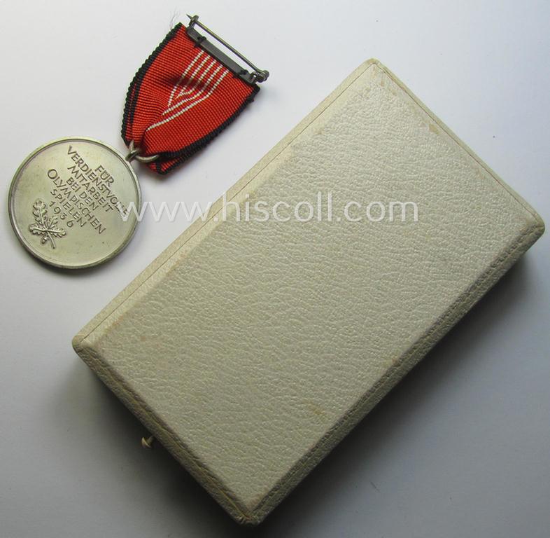 'Deutsche Olympia-Erinnerungsmedaille 1936' being a non-maker-marked example that comes mounted onto its original ribbon (ie. 'Bandabschnitt') and that comes stored in its typical, beige-white-coloured etui