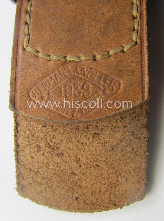 WH (Heeres) 'standard-pattern', field-grey-toned- and aluminium-based belt-buckle being a maker- (ie. 'Hermann Knoller - Pforzheim'-) marked- and/or: '1939'-dated example that comes mounted onto its leather-based tab
