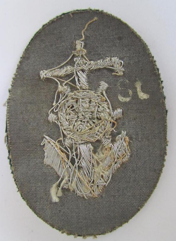 Neat, WH (Heeres) trade- and/or special-career insignia, being a detailed- and/or neatly hand-embroidered example as executed on darker-green-coloured wool, as was intended for a: 'Steuermann' (ie. enigineer-boat-pilot or helmsman)