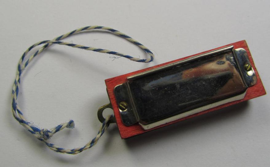 Unusally seen so-called: WHW- (ie. 'Winterhilfswerke'-) related miniature harmonica entitled: 'WHW - Gau Berlin' that comes mounted on its original cord