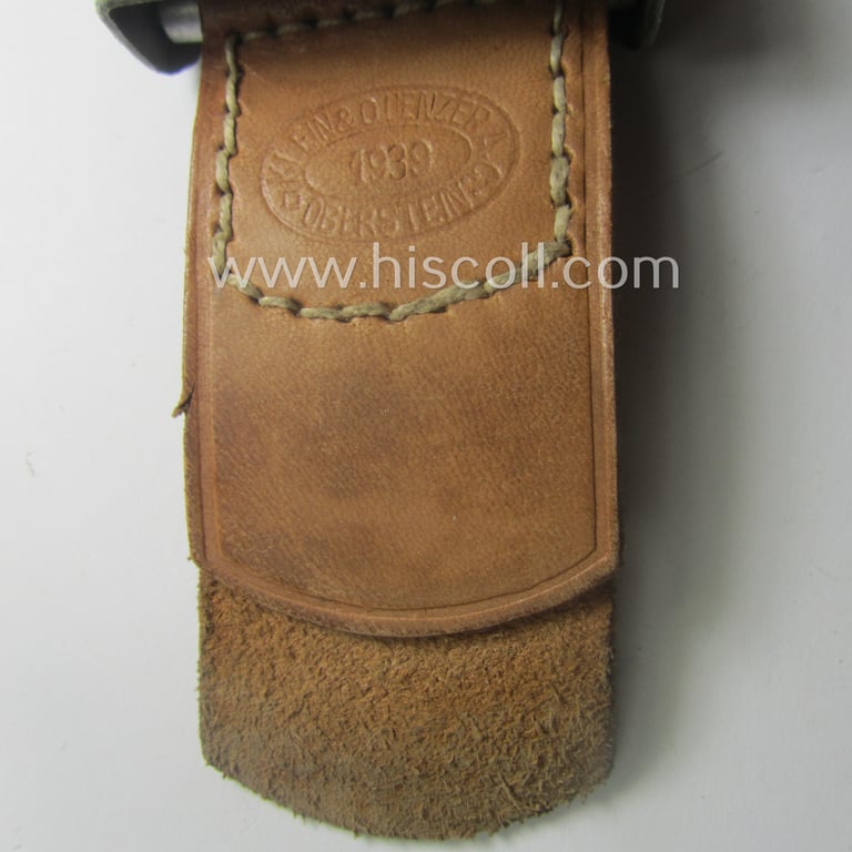 WH (Heeres) 'standard-pattern', field-grey-toned- and aluminium-based belt-buckle being a maker- (ie. 'Steinhauer & Lück'-) marked- and/or: '1939'-dated example that comes mounted onto its leather-based tab