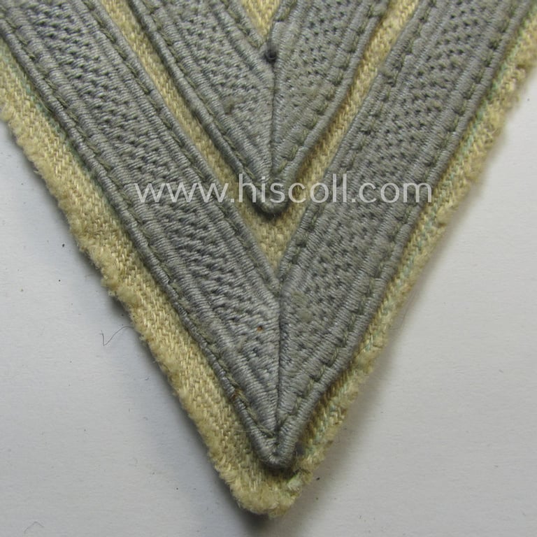 WH (Luftwaffe) 'Armwinkel' (or: arm-chevron) as executed on typical beige- (ie. tan-) coloured 'HBT'-styled linnen as was specifically intended for usage by a soldier with the rank of an: 'Obergefreiter'
