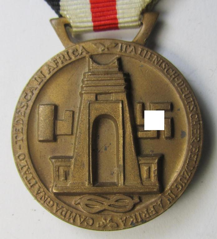 Superb, golden-bronze-coloured- (and I deem 'Buntmetall'-based-) example of a: 'Deutsch-Italienische Feldzugsmedaille' (or: German-Italian campaign medal) that comes mounted onto its (regular-sized) piece of original (albeit minimally faded) ribb...