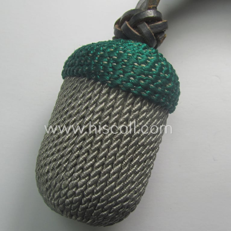 Bright-green- and silver-coloured, EM- (ie. NCO-) type side-arm knot (ie. 'Portepee' ie.: 'Troddel') as was used for the various WH-bayonets and that comes in an overall very nice- (ie. 'virtually mint- ie. unissued'-), condition