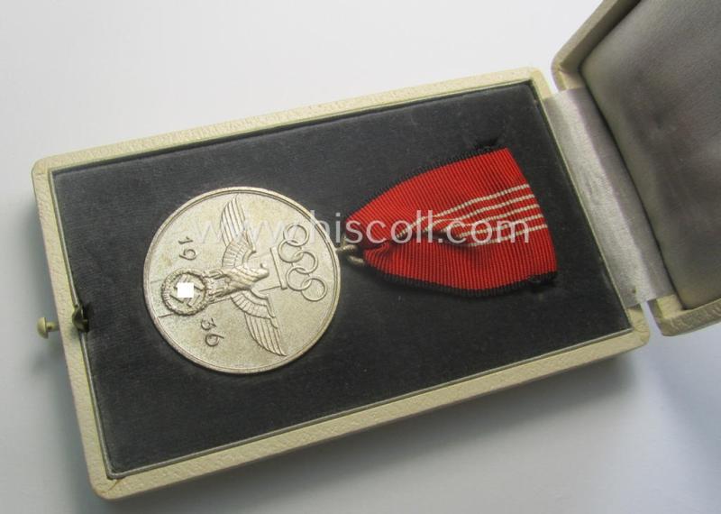 'Deutsche Olympia-Erinnerungsmedaille 1936' being a non-maker-marked example that comes mounted onto its original ribbon (ie. 'Bandabschnitt') and that comes stored in its typical, beige-white-coloured etui