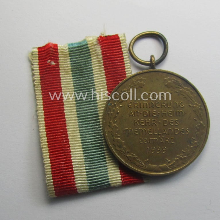 WH Memelland 'Anschluss'- (ie. occupation-) medal: '22 März 1939' (being a minimally used example of the so-called: 'slanted G'-type) that comes together with its original non-confectioned ribbon (ie. 'Bandabschnitt')