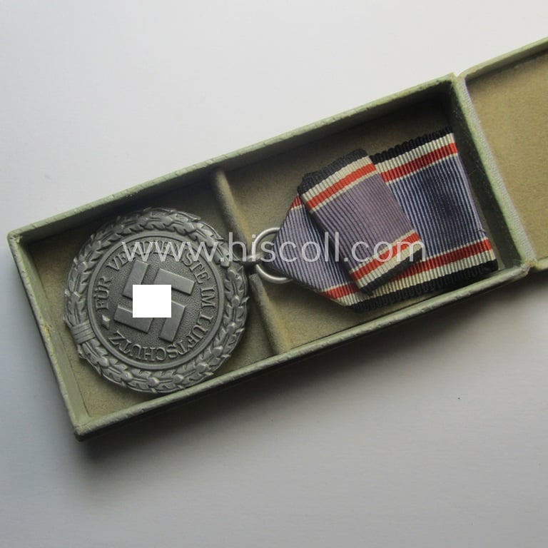 Light-weight (ie. typical aluminium-based) medal (and accompanying ribbon-bar!) as was intended for air-raid wardens 2nd. class (or: 'Luftschutz-Ehrenzeichen 2. Stufe') that comes stored in its period, dove-grey-coloured etui