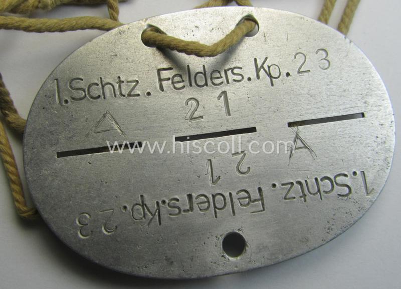 Aluminium-based, WH (Heeres) ie. 'Infanterie-Truppen'-related ID-disc bearing the clearly stamped unit-designation: '1. Schtz.Felders.Kp. 23' and that comes mounted onto its period cord as issued and worn