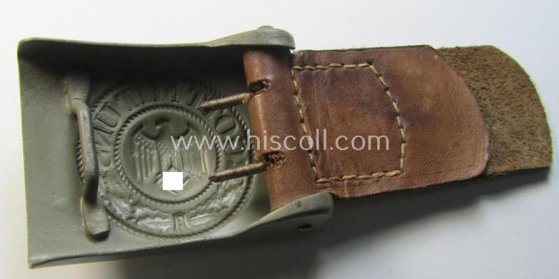Superb, WH (Heeres) field-grey-coloured- and/or steel-based belt-buckle being (an unusally seen!) non-maker-marked- nor dated example that comes mounted onto its (light-brown-coloured) leather-based tab and that comes in a wonderful condition