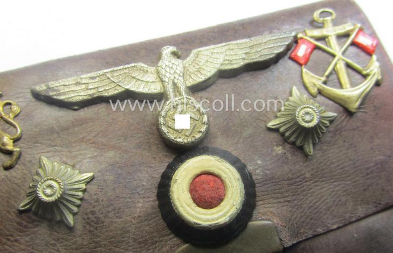 Unusual, WH (Kriegsmarine) item that comes as a 'period-souvenir': a leather-based 'wallet' that holds various Kriegsmarine-insignia (such as a visor-cap-eagle, cocarde, 2 pips, signals-'Auflage' and an (unidentified) 'Lion'-badge