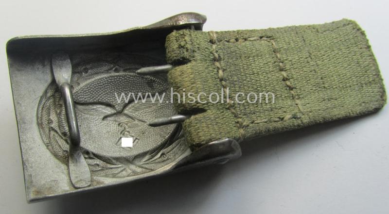 WH (Luftwaffe) 'tropical-issued' belt-buckle being a non-maker-marked, greyish-silver-coloured example that comes mounted onto its original, greenish-coloured- (and/or: 'webbing'-based-) tab