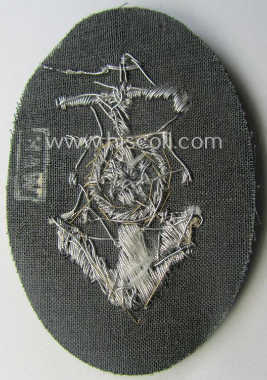 WH (Heeres) trade- and/or special-career insignia being a detailed- and/or neatly hand-embroidered example as executed on darker-green-coloured wool as was intended for a: 'Steuermann' (ie. enigineer-boat-pilot or helmsman)