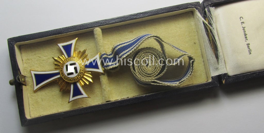 By 'C.E. Juncker-produced 'Ehrenkreuz der deutschen Mutter - erste Stufe' (or mothers'-cross in gold) that comes stored in its original and/or neatly maker- (ie. 'C.E. Juncker - Berlin'-) marked etui