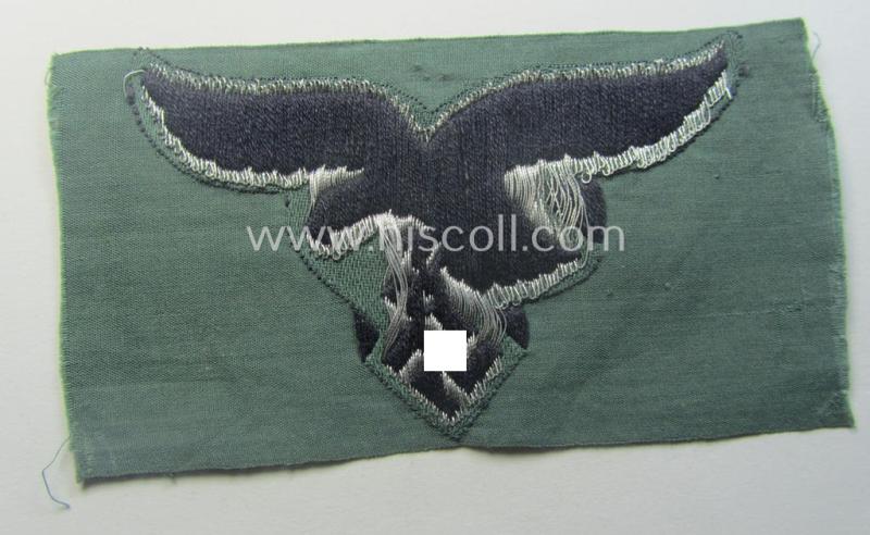 WH (Luftwaffe) officers'- (ie. evt. NCO-) type breasteagle (ie. 'Brustadler') as was executed in neatly machine-woven silver-coloured thread (ie. 'flatwire-style') onto a darker-blue- (ie. field-grey-) coloured- and/or linnen-based background