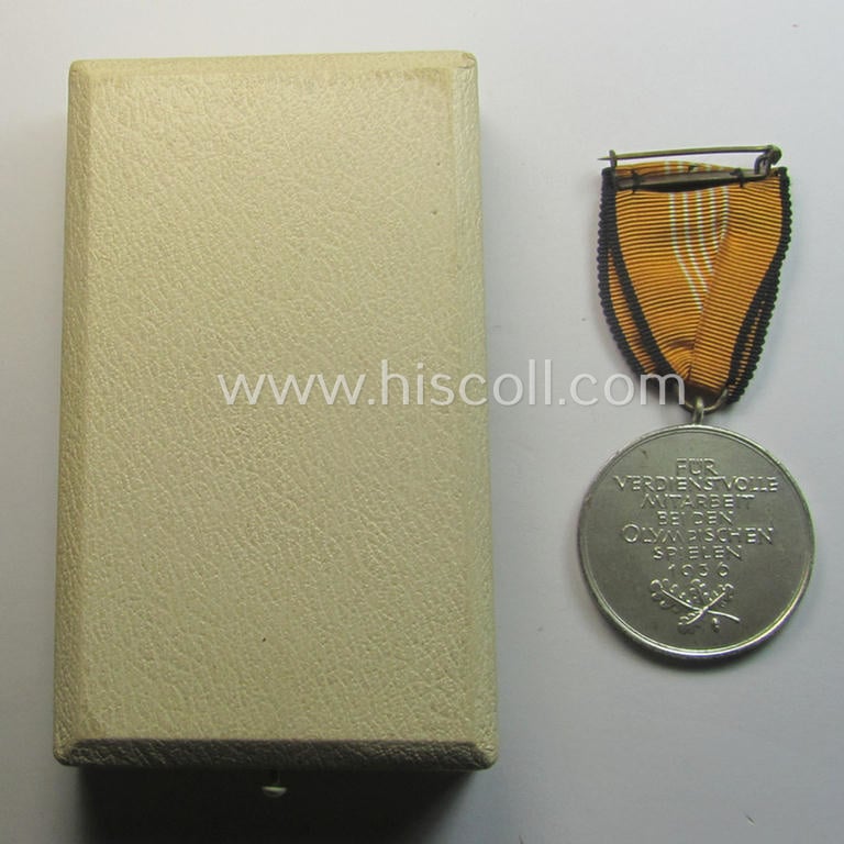 'Deutsche Olympia-Erinnerungsmedaille 1936' being a non-maker-marked example that comes mounted onto its original ribbon (ie. 'Bandabschnitt') and that comes stored in its typical, beige-white-coloured etui