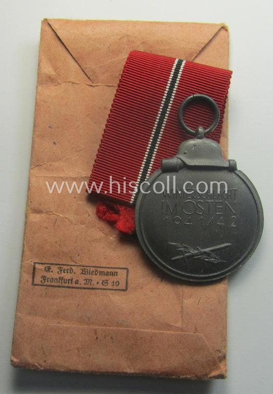 Neatly maker- (ie. '19'-) marked medal: 'Winterschlacht im Osten 1941/42' that came stored in its period pouch by the company: 'E. Ferd. Wiedmann'