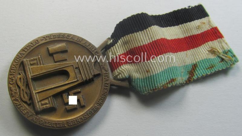 Golden-bronze-coloured- (and I deem 'Buntmetall'-based-) example of a: 'Deutsch-Italienische Feldzugsmedaille' (or: German-Italian campaign-medal) that comes mounted onto its (regular-sized) piece of original (and minimally faded- ie. stained!) r...