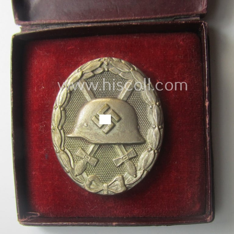 Silver-class wound-badge- (or: 'Verwundeten-Abzeichen in Silber'-) set comprising of a non-maker-marked example as produced by an unidentified 'Hersteller' and that comes stored in its typical 'LDO'-styled etui