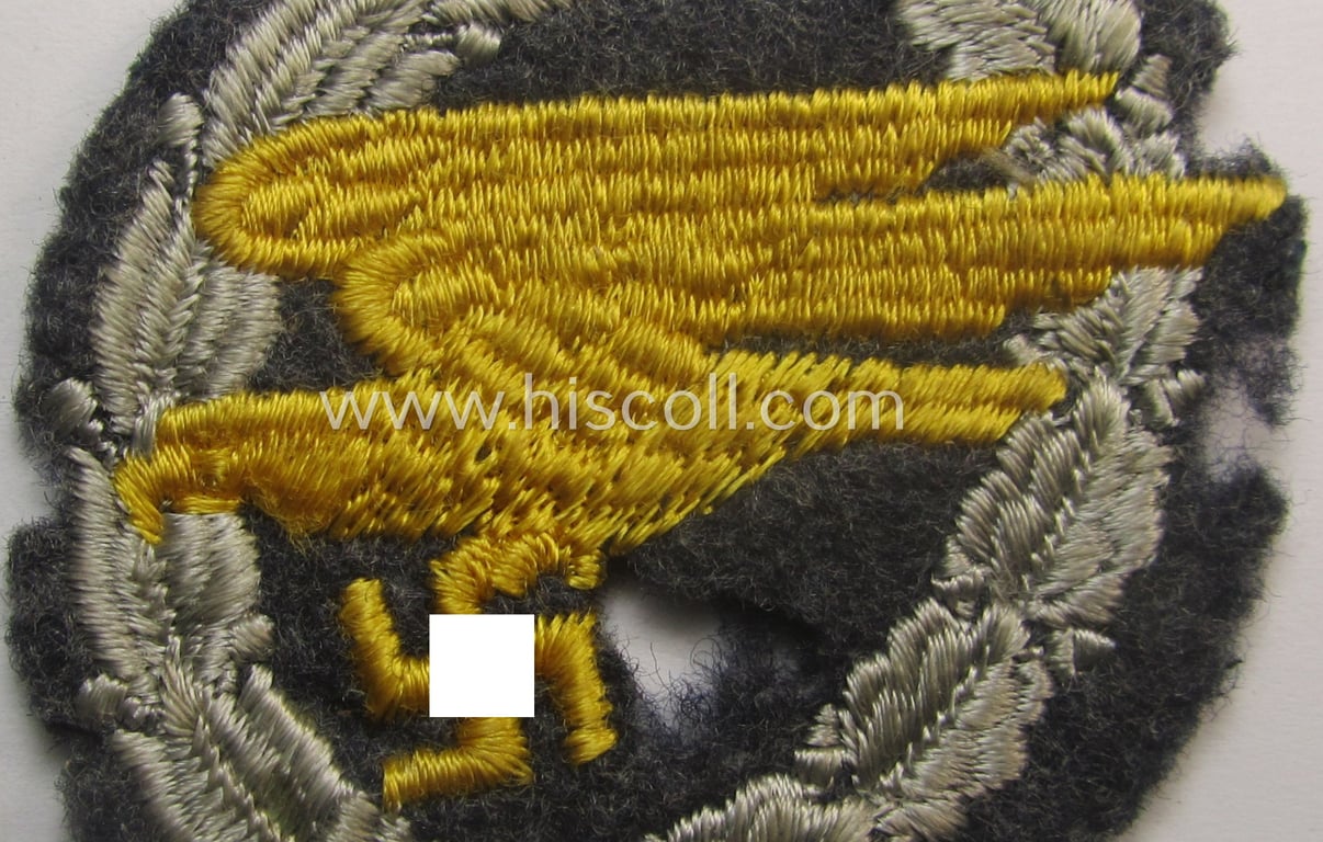 Truly used- and/or carefully tunic-removed, WH (Luftwaffe) 'Fallschirmschützen-Abzeichen in Stoff' (or: cloth-based paratroopers'-jump-badge) being a nicely machine-embroidered 'relic' specimen that comes in a clearly used- ie. worn, condition