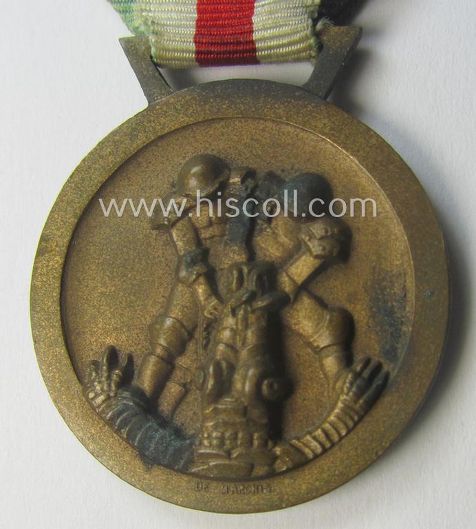 Golden-bronze-coloured- (and I deem 'Buntmetall'-based-) example of a: 'Deutsch-Italienische Feldzugsmedaille' (or: German-Italian campaign-medal) that comes mounted onto its (regular-sized) piece of original (and minimally faded!) ribbon