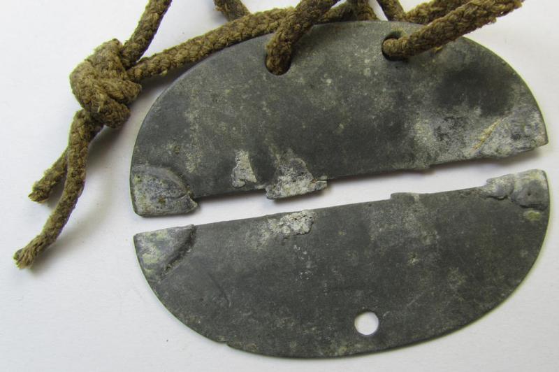 Zinc-based - albeit broken in two parts - WH (Heeres) 'Artillerie'-related ID-disc bearing the clearly stamped unit-designation that reads: 'Schw.Art.Abt.(mot.) 53 - 6 Bttr.' and that comes mounted onto its period cord as issued- and/or worn