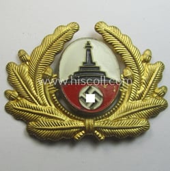 Tin-based- and/or: bright-golden-coloured (ie. painted) visor-cap-badge ie. wreath...