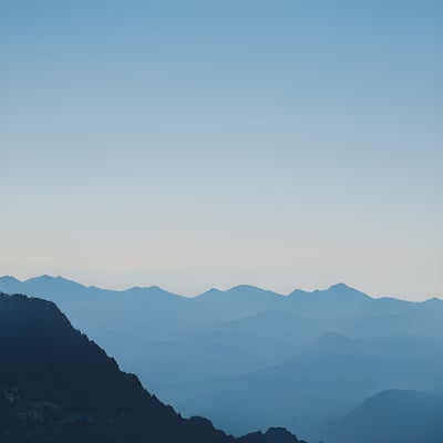 A view of a mountain range from the top of a hill