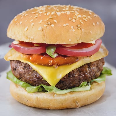 A cheeseburger with tomatoes, lettuce and onions